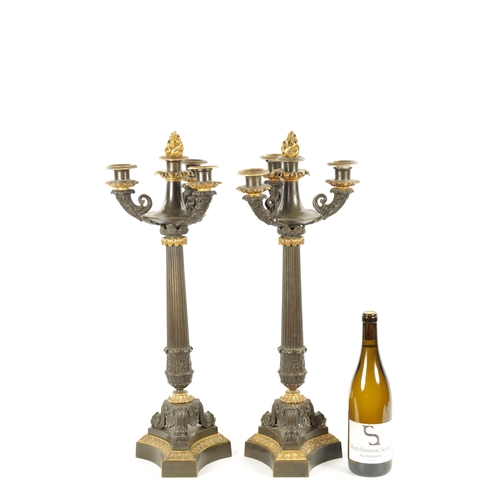 1023 - A PAIR OF REGENCY BRONZE AND ORMOLU THREE BRANCH CANDELABRA having leaf cast decoration throughout w... 