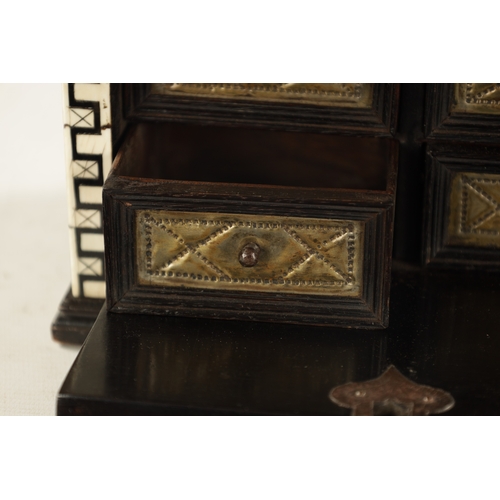 1051 - A 17TH CENTURY GERMAN EBONY AND IVORY MINIATURE TABLE CABINET having foliate inlaid panels, the cham... 