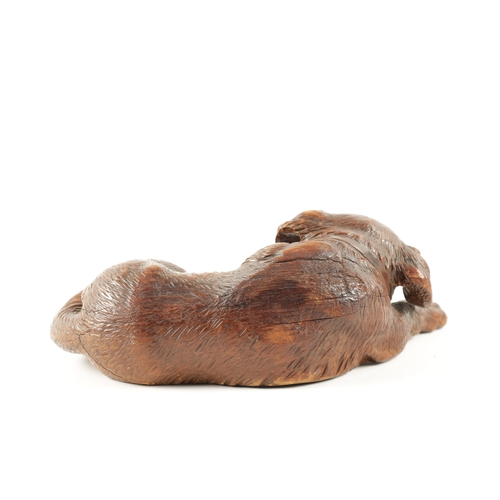 1053 - A 19TH CENTURY BLACK FOREST CARVED LINDEN WOOD DOG SCULPTURE set with glass eyes and seated in a rec... 