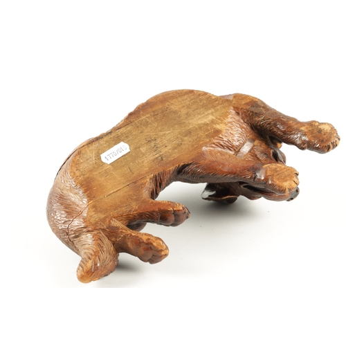 1053 - A 19TH CENTURY BLACK FOREST CARVED LINDEN WOOD DOG SCULPTURE set with glass eyes and seated in a rec... 