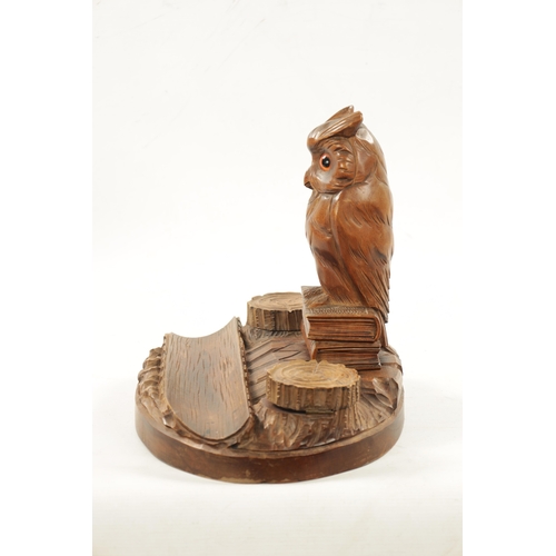 1064 - AN EARLY 20TH CENTURY CARVED FRUITWOOD BLACK FOREST INKWELL having a owl seated on two books raised ... 