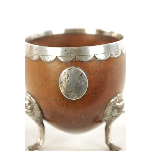 1093 - AN 18TH CENTURY SILVER MOUNTED CARVED COCONUT CUP with lion mask and paw feet, scalloped rim and app... 