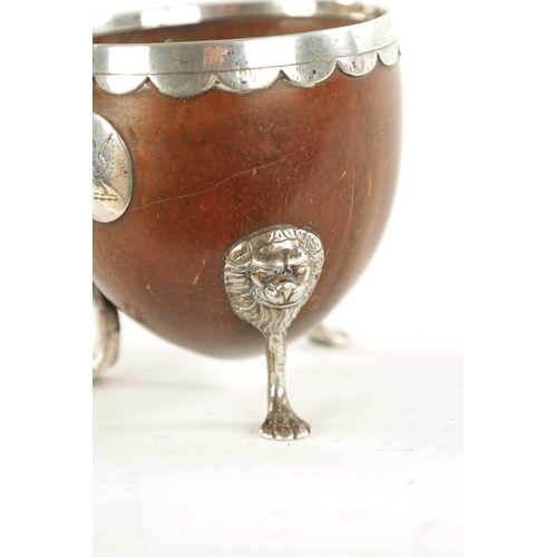 1093 - AN 18TH CENTURY SILVER MOUNTED CARVED COCONUT CUP with lion mask and paw feet, scalloped rim and app... 