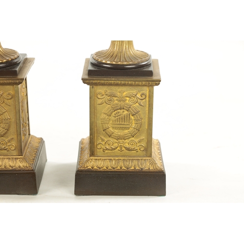 930 - A PAIR OF 19TH CENTURY BRONZED GILT CAST IRON URNS of classical design on square pedestal bases (35c... 