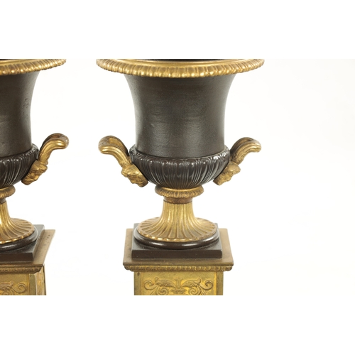 930 - A PAIR OF 19TH CENTURY BRONZED GILT CAST IRON URNS of classical design on square pedestal bases (35c... 