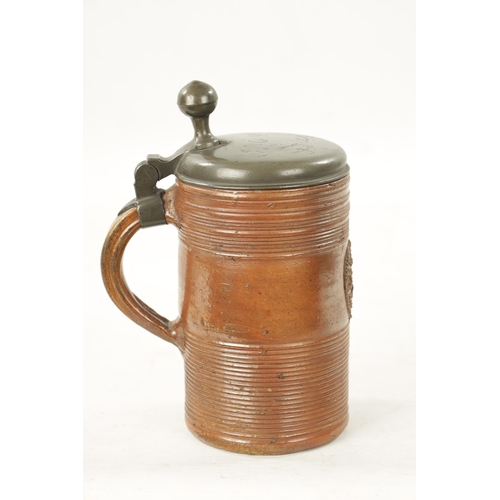 946 - AN EARLY 18TH CENTURY PILSENER EUROPEAN ALE JUG with terracotta body and engraved pewter lid (22cm h... 