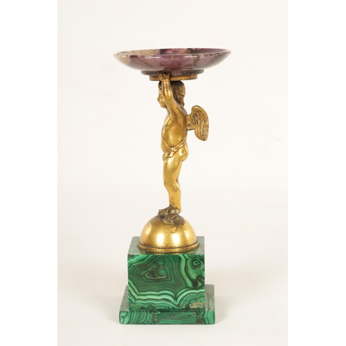 964 - A REGENCY FIGURAL GILT BRONZE, MALACHITE AND BLUE JOHN TAZZA modelled as a gilt bronze winged cherub... 