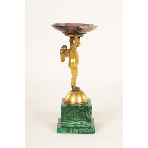 964 - A REGENCY FIGURAL GILT BRONZE, MALACHITE AND BLUE JOHN TAZZA modelled as a gilt bronze winged cherub... 