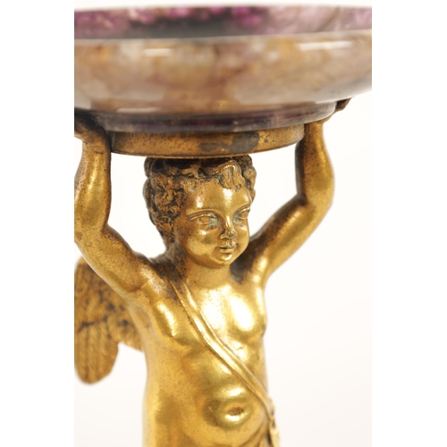 964 - A REGENCY FIGURAL GILT BRONZE, MALACHITE AND BLUE JOHN TAZZA modelled as a gilt bronze winged cherub... 