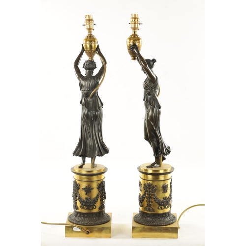 973 - A PAIR OF REGENCY GILT AND BRONZE FIGURAL LAMP BASES depicting standing females holding urns; raised... 