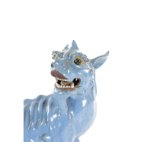 127 - A 19TH CENTURY CHINESE BLUE GLAZED SEATED FOO DOG with painted character marks beneath. (18cm high)