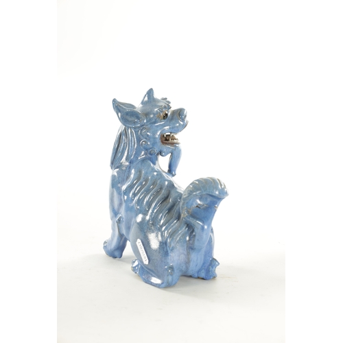 127 - A 19TH CENTURY CHINESE BLUE GLAZED SEATED FOO DOG with painted character marks beneath. (18cm high)