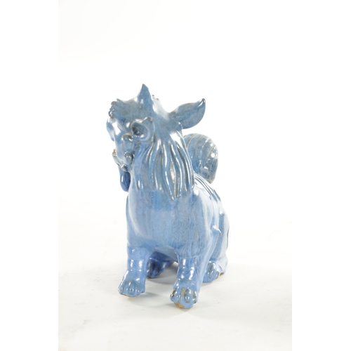 127 - A 19TH CENTURY CHINESE BLUE GLAZED SEATED FOO DOG with painted character marks beneath. (18cm high)