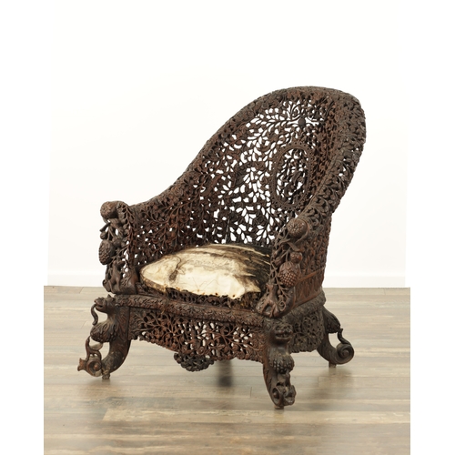 134 - A 19TH CENTURY CARVED HARDWOOD INDIAN ARMCHAIR profusely carved and pierced with leafwork and animal... 