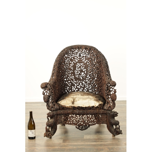 134 - A 19TH CENTURY CARVED HARDWOOD INDIAN ARMCHAIR profusely carved and pierced with leafwork and animal... 