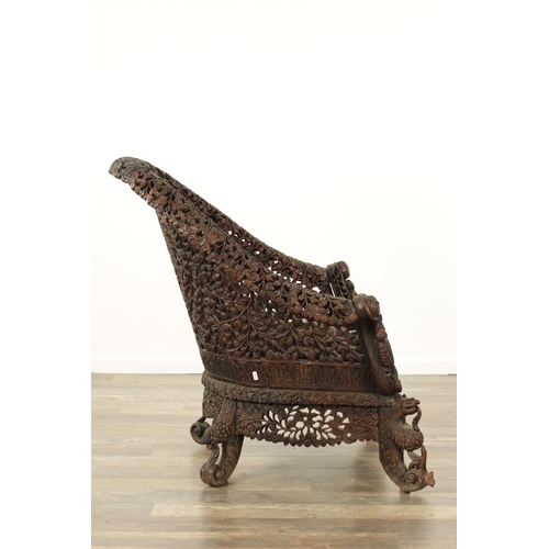 134 - A 19TH CENTURY CARVED HARDWOOD INDIAN ARMCHAIR profusely carved and pierced with leafwork and animal... 