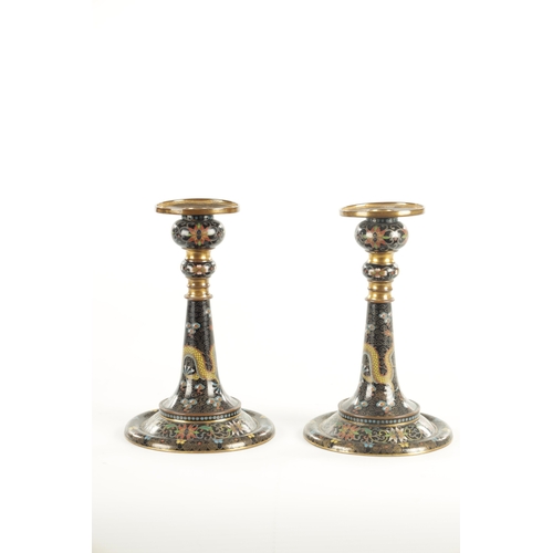 137 - A PAIR OF EARLY 20TH CENTURY CHINESE CLOISONNE CANDLESTICKS decorated with five claw dragons on a bl... 