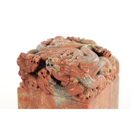 140 - A LARGE CHINESE CARVED ROUGE SOAPSTONE SEAL with entwined dragons amongst foliage to the top, having... 
