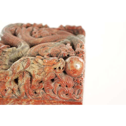 140 - A LARGE CHINESE CARVED ROUGE SOAPSTONE SEAL with entwined dragons amongst foliage to the top, having... 