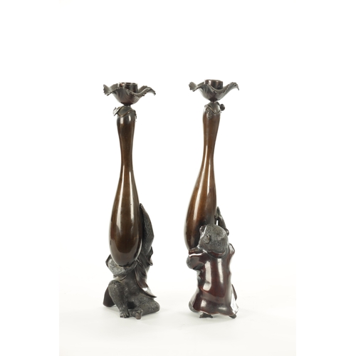 212 - A FINE PAIR OF JAPANESE MEIJI PATINATED BRONZE FIGURAL CANDLESTICKS the plain slender ovoid vase-sha... 