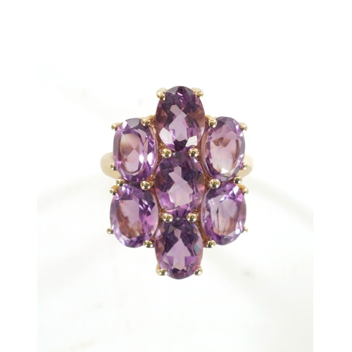 311 - A 10K YELLOW GOLD AMETHYST DRESS RING with a large shaped seven stone cluster setting. 5.26g. Ring s... 