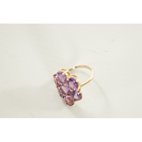 311 - A 10K YELLOW GOLD AMETHYST DRESS RING with a large shaped seven stone cluster setting. 5.26g. Ring s... 