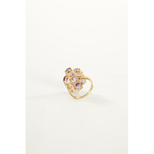 311 - A 10K YELLOW GOLD AMETHYST DRESS RING with a large shaped seven stone cluster setting. 5.26g. Ring s... 