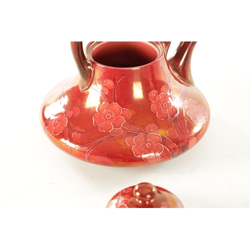 33 - AN EARLY 20TH CENTURY MOORCROFT POTTERY PRUNUS PATTERN RUBY LUSTRE TEAPOT having a shaped body with ... 