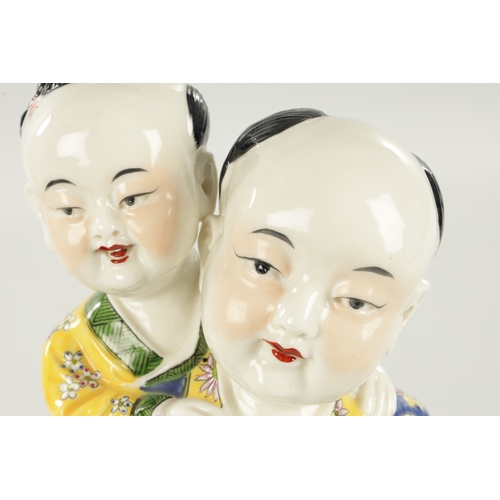 94 - A LATE 19TH CENTURY CHINESE PORCELAIN FIGURE modelled as a boy giving a piggyback dressed in brightl... 