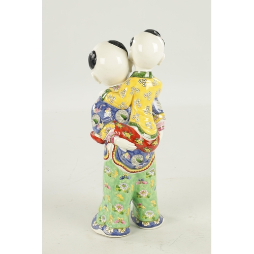 94 - A LATE 19TH CENTURY CHINESE PORCELAIN FIGURE modelled as a boy giving a piggyback dressed in brightl... 