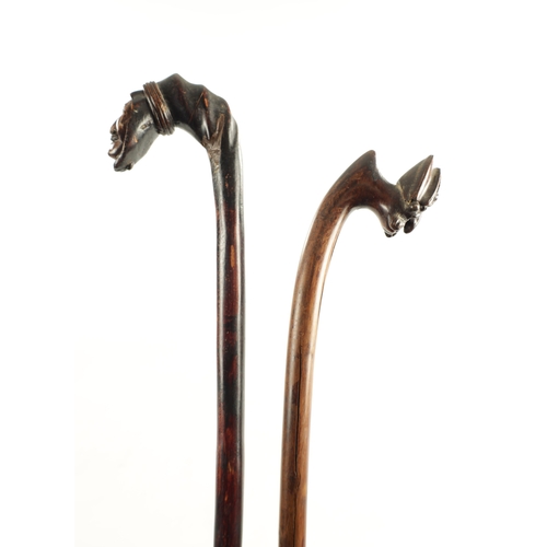 734 - TWO 19TH CENTURY FOLK ART CARVED FRUITWOOD WALKING STICKS having carved mask head handles (96cm and ... 