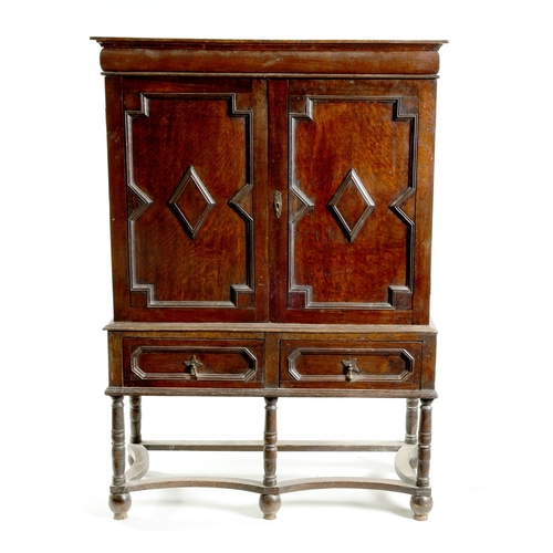 1414 - AN EARLY 18TH CENTURY OAK GEOMETRIC MOULDED CABINET ON STAND with cushion moulded cornice above a pa... 