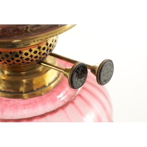 685 - A GOOD VICTORIAN CRANBERRY GLASS AND BRASS OIL LAMP with black pottery foot and stylised leaf work b... 