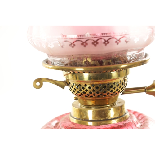 685 - A GOOD VICTORIAN CRANBERRY GLASS AND BRASS OIL LAMP with black pottery foot and stylised leaf work b... 