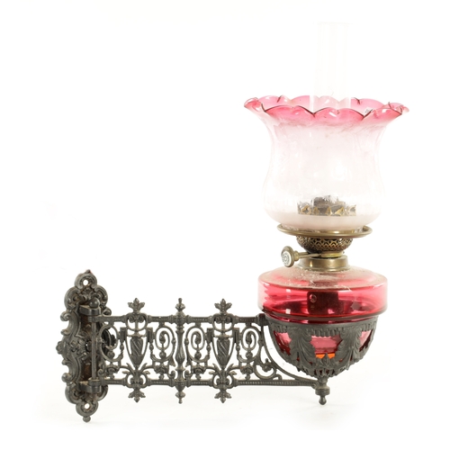 704 - A 19TH CENTURY HANGING CAST IRON AND CRANBERRY OIL LAMP with decorative cast-hinged arm and lift-out... 