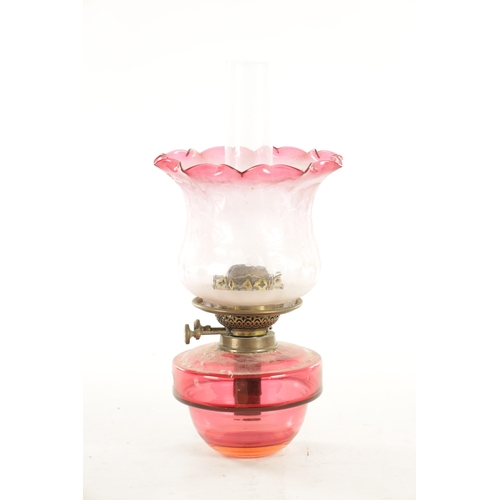 704 - A 19TH CENTURY HANGING CAST IRON AND CRANBERRY OIL LAMP with decorative cast-hinged arm and lift-out... 