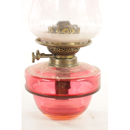 704 - A 19TH CENTURY HANGING CAST IRON AND CRANBERRY OIL LAMP with decorative cast-hinged arm and lift-out... 