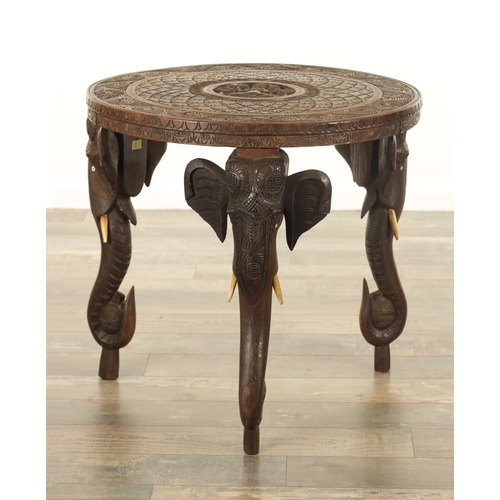 143 - A 19TH CENTURY INDIAN CARVED HARDWOOD OCCASIONAL TABLE the circular carved top above three elephant'... 