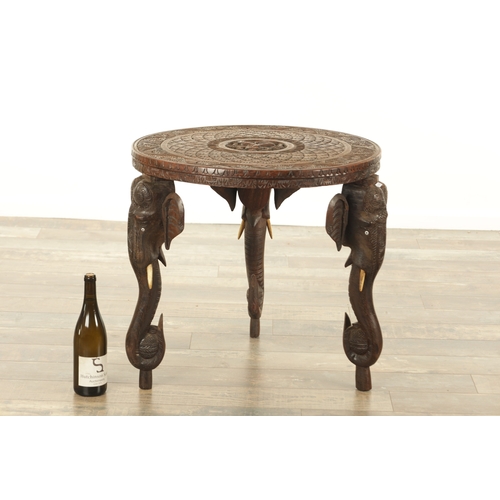 143 - A 19TH CENTURY INDIAN CARVED HARDWOOD OCCASIONAL TABLE the circular carved top above three elephant'... 