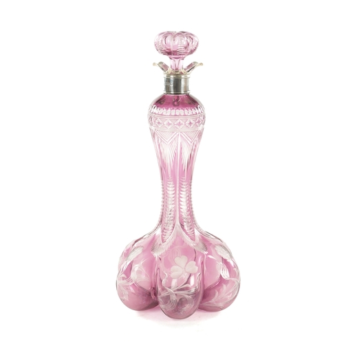 26 - AN EARLY 20TH CENTURY SILVER TOPPED INTAGLIO CUT GLASS PINK TINTED DECANTER decorated with flower he... 