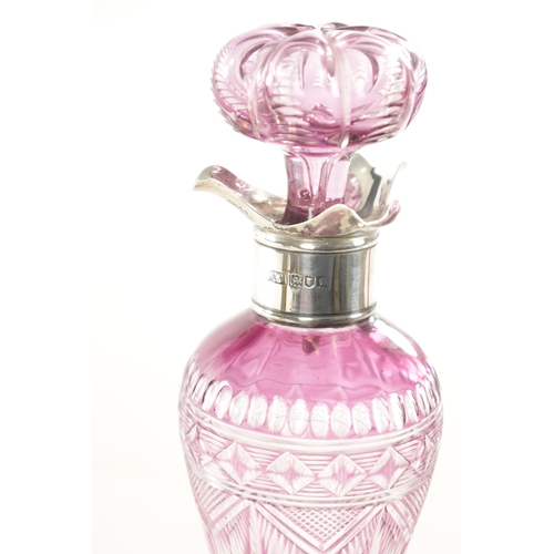 26 - AN EARLY 20TH CENTURY SILVER TOPPED INTAGLIO CUT GLASS PINK TINTED DECANTER decorated with flower he... 