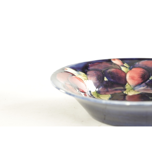 69 - A 1930'S MOORCROFT LARGE SHALLOW FRUIT DISH with inverted rim decorated in the big pansy pattern on ... 