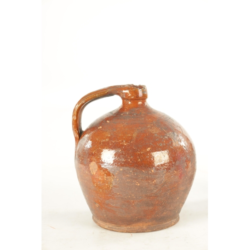 76 - AN EARLY BROWN GLAZED TERRACOTTA WINE JAR of shouldered form with ribbed handle. (21cm high)