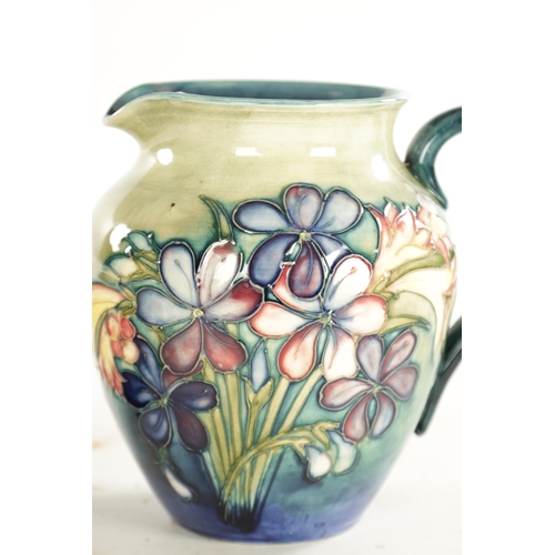 85 - A 1940'S WALTER MOORCROFT JUG incised and decorated with freesia sprays on a shaded turquoise ground... 