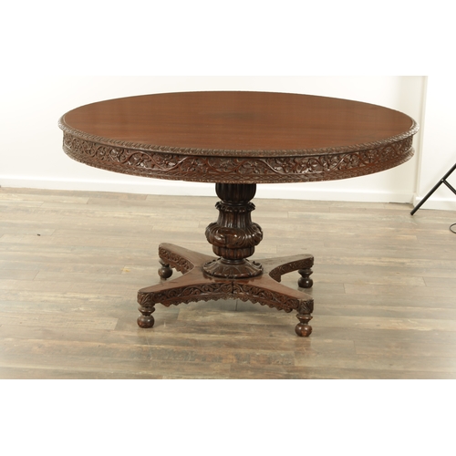 176 - A LARGE EARLY 19TH CENTURY INDIAN HARDWOOD CENTRE TABLE with carved floral frieze raised on a bulbou... 