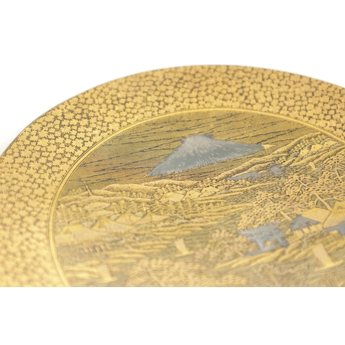 139 - A JAPANESE MEIJI PERIOD GILT BRONZE KOMAI PLATE finely decorated with houses and a mill below Mount ... 