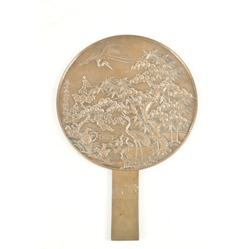 179 - A JAPANESE SILVERED BRONZE HAND MIRROR with relief cast front decorated with blooming trees and stor... 