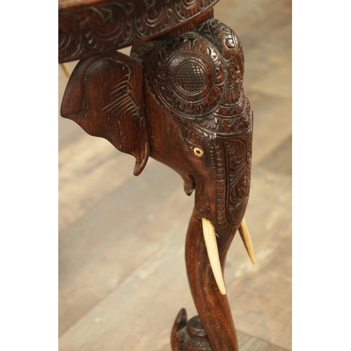 245 - A 19TH CENTURY INDIAN CARVED HARDWOOD OCCASIONAL TABLE the circular carved top above three elephant'... 