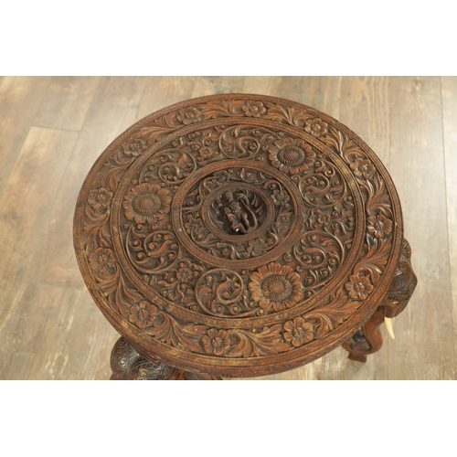 245 - A 19TH CENTURY INDIAN CARVED HARDWOOD OCCASIONAL TABLE the circular carved top above three elephant'... 