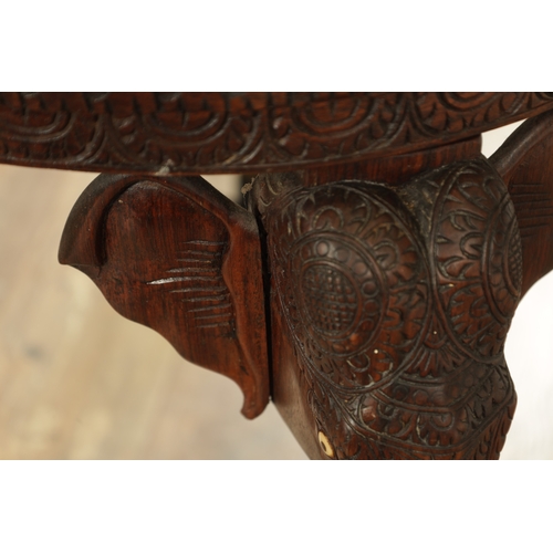 245 - A 19TH CENTURY INDIAN CARVED HARDWOOD OCCASIONAL TABLE the circular carved top above three elephant'... 